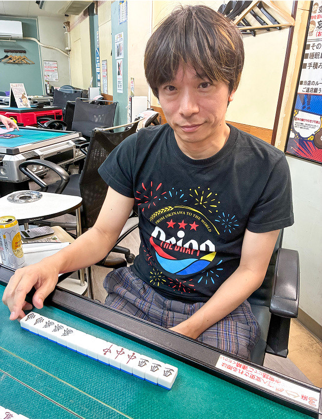 雀荘の卓で手牌を並べる塚本 憲弘