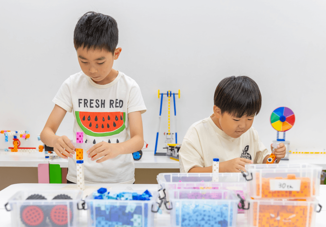 ブロックやパーツを使ってロボットを組み立てる子どもたち